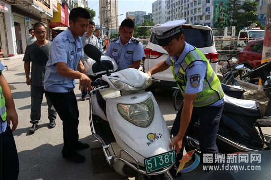 交警将占道停靠的电瓶车搬进指定停靠点.jpg