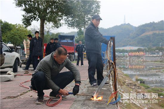 电焊工人在执法人员的指导下，拆除人行道外的铁栅栏，这些铁栅栏为非法私建物品。.jpg